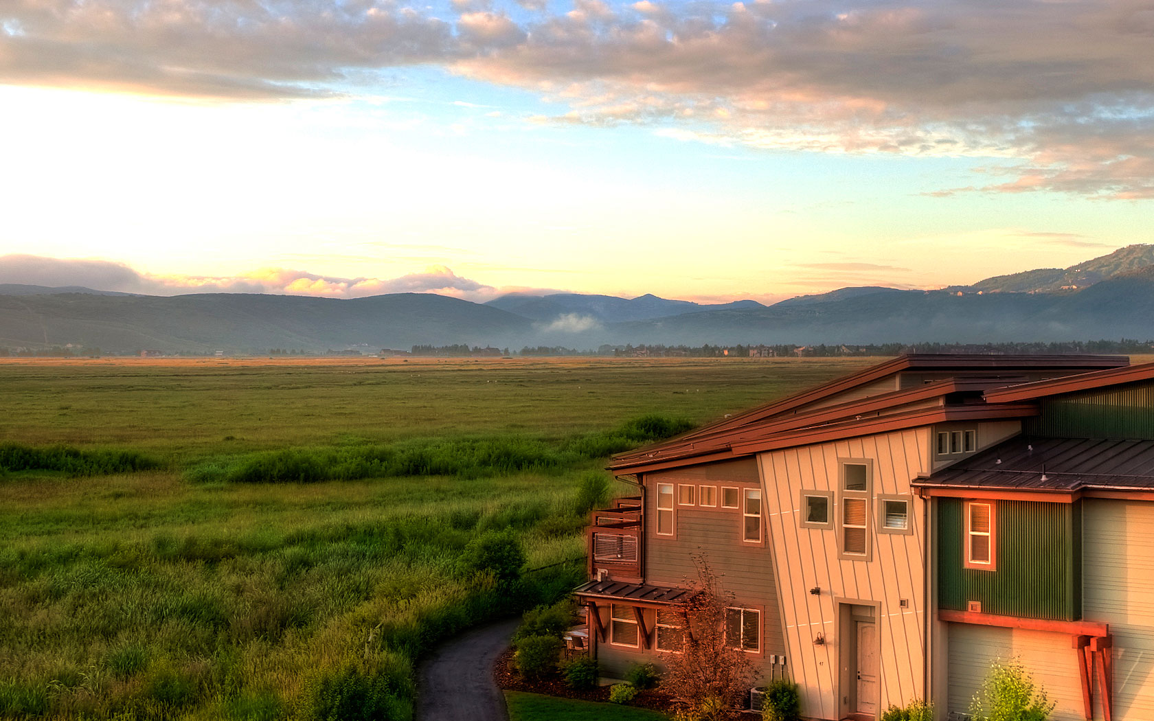photo of resort with green fields behind it and mountains